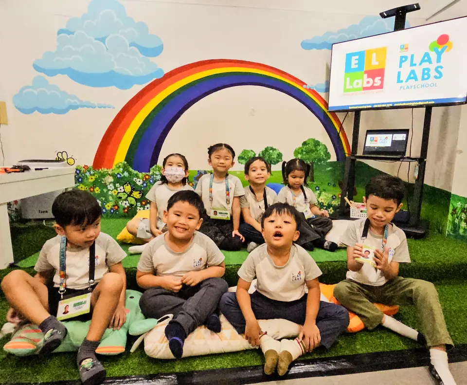 ELLabs class sitting together under the rainbow mural