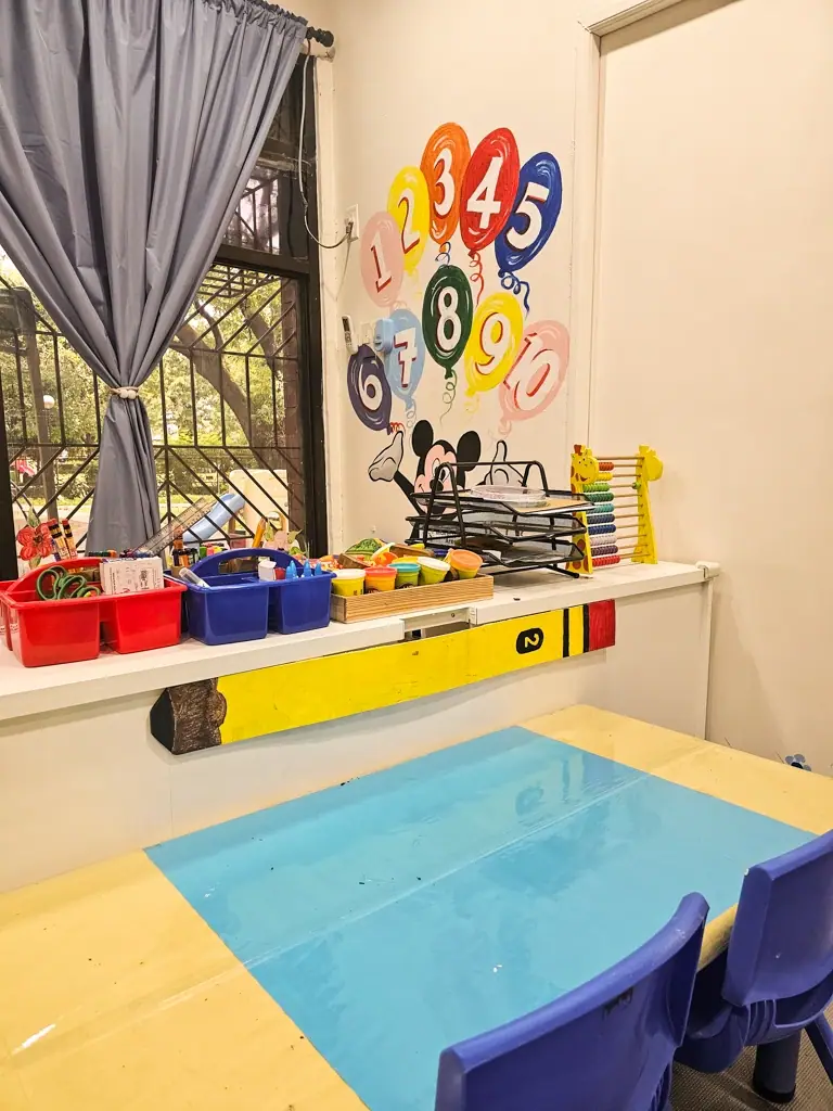 Water play table below a colorful counting wall