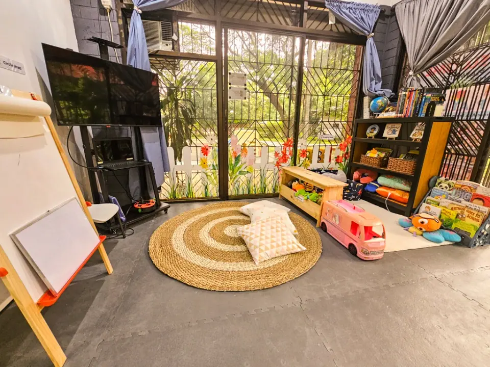 Glass-walled play room with a woven rug and a toy bus