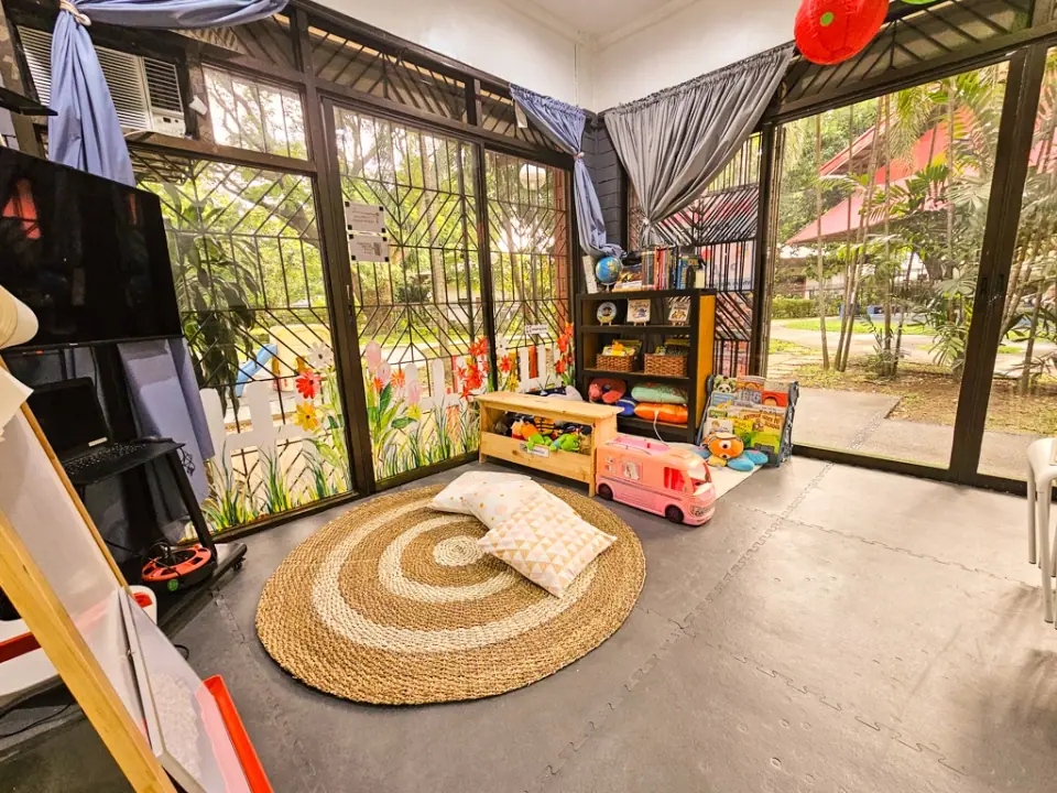 Play room with a toy bus and shelves by the garden windows